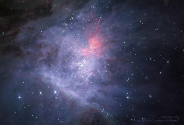 The center of the Orion Nebula is seen in infrared light as imaged by the James Webb Space Telescope. In the center is the Trapezium Star Cluster. The main image is in near infrared light, while the rollover image is in mid-infrared light.