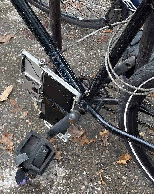 Silver MacBook Pro bottom plate with wire and lock tether, used as a lock for a black fixie bike