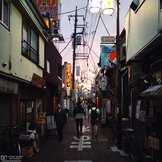At Star Road in Asagaya, Tokyo, pedestrians are walking between the many small shops and eateries that are typical for this area. (View at dusk)