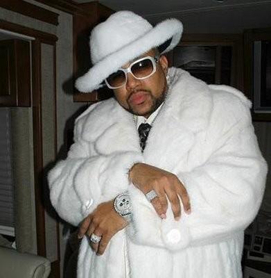 Rapper Pimp C wearing dark shades and a white fur coat. 