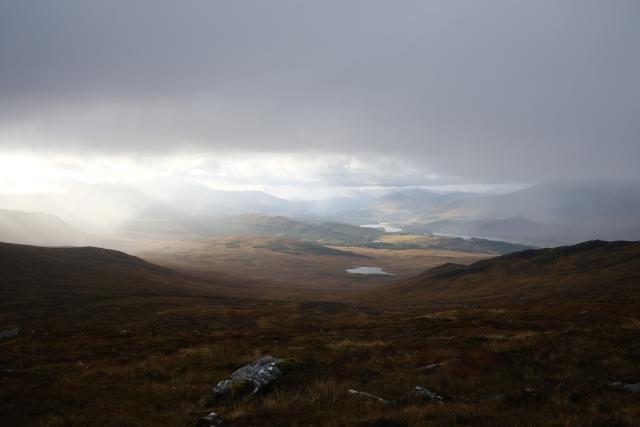 View out from a hill over towards loch lagan. The cloud is thick overhead with sunlight just illuminating the lower ground