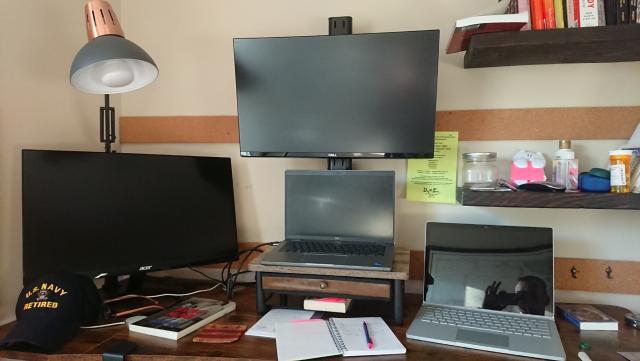 A picture of Nick's office. There's a laptop in the middle, a monitor on top, a monitor to the left, and another laptop to the right.