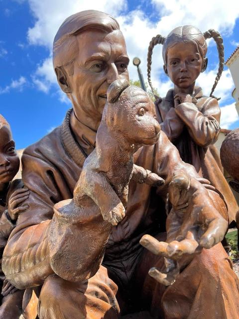 Mister Rogers sculpture close up showing details of his face holding a puppy.