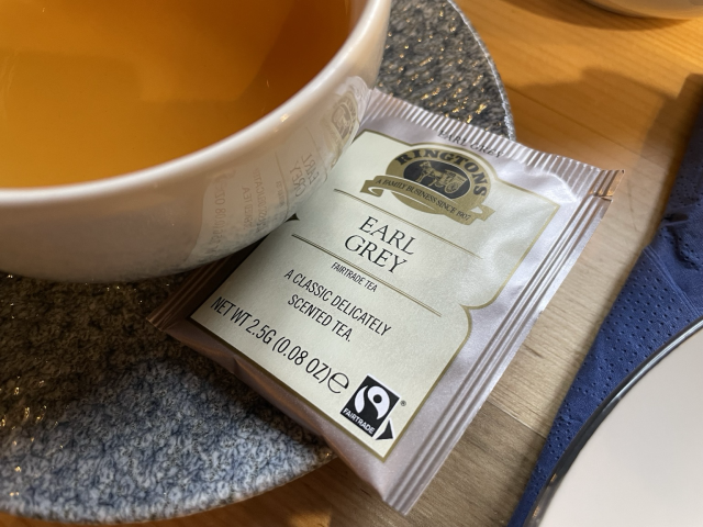 An Earl Grey tea bag by the company called Ringtons on a saucer of a tea cup.