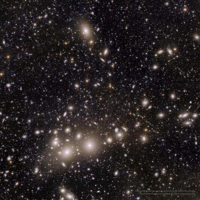 A deep space image showing many galaxies, some of which are seen in a central bar running nearly horizontally across the image.