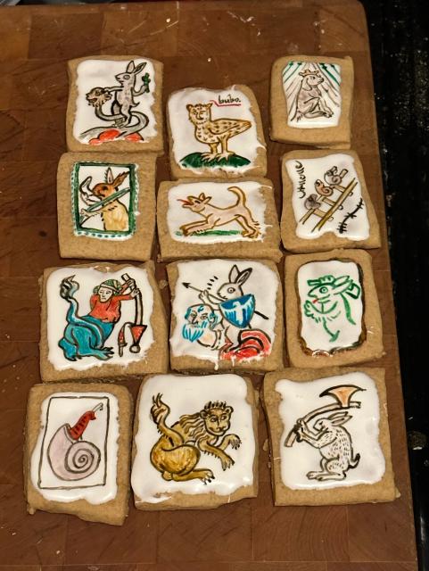 Twelve cookies hand decorated with fanciful medieval creatures such as a hunting squirrel and two rabbit knights