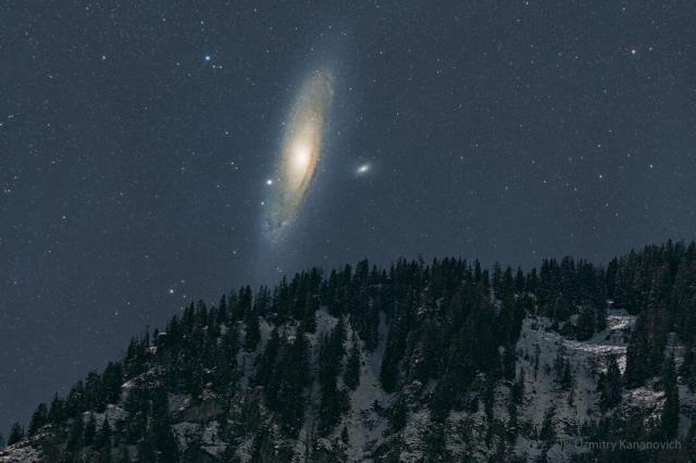 The night sky over a snowy mountain is shown, with the dark sky dominated by a large spiral galaxy -- the Andromeda galaxy.