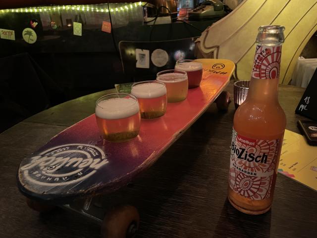 A literal skateboard with holes for beer glasses drilled into it, filled with 4 different kinds of beer. 