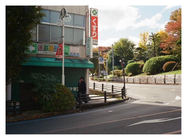 Film Photograph of a couple turning a corner in Urawa, with some pretty autumn foliage in the background.
