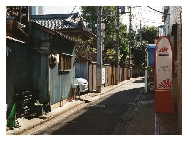 A car peeks out of an alleyway, divided into ight and shadow.