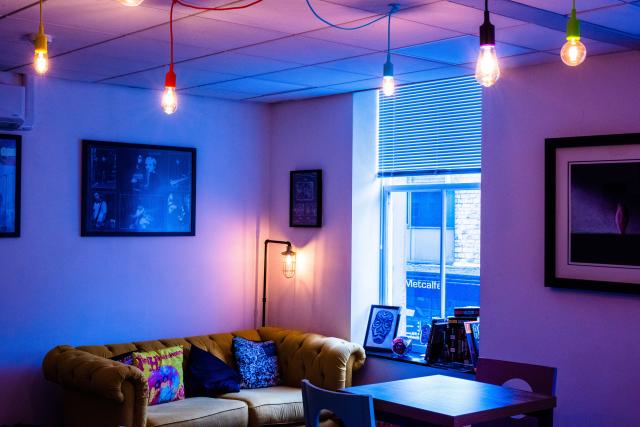 Picture of Upstairs of Wax and Beans with a sofa and coloured light sockets hanging. 