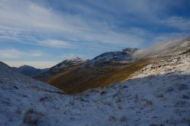 view from between two snowy slopes to two higher peaks caught in the sun