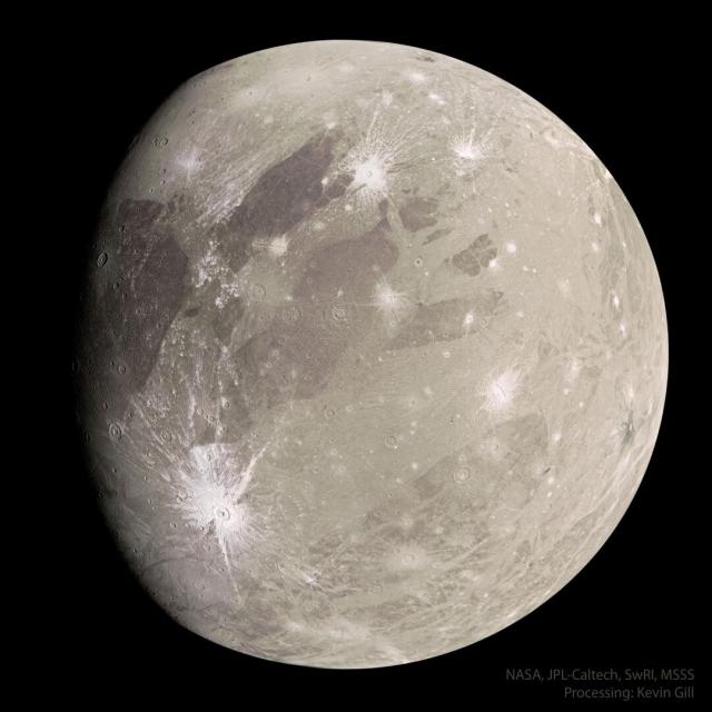 A tan sphere is shown with dark markings and a few light craters. The sphere is the largest known moon in the Solar System: Jupiter's moon Ganymede.