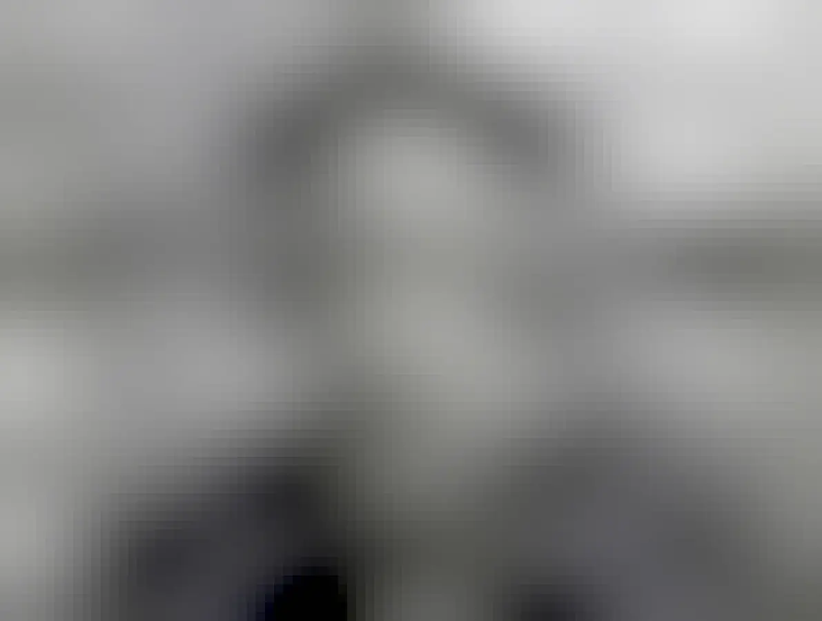 A male-presenting 50-60 year old in a hat speaking on a documentary with a mast in the background.