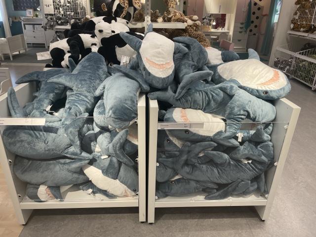 A container in IKEA containing many Shark plushies (blåhaj) in a “pile” manner
