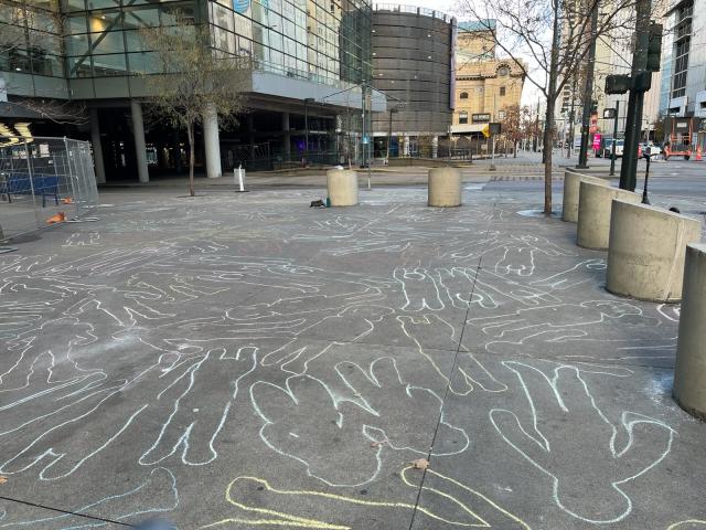 Dozens of chalk outlines of children drawn on the sidewalk in front of Denver's Convention Center, hosting the Jewish National Fund.