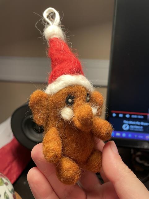 A Mastodon made out of wool wearing a Santa hat. 