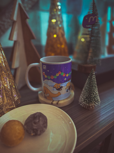 A cup of tea and timbits next to a forest of Christmas decorations