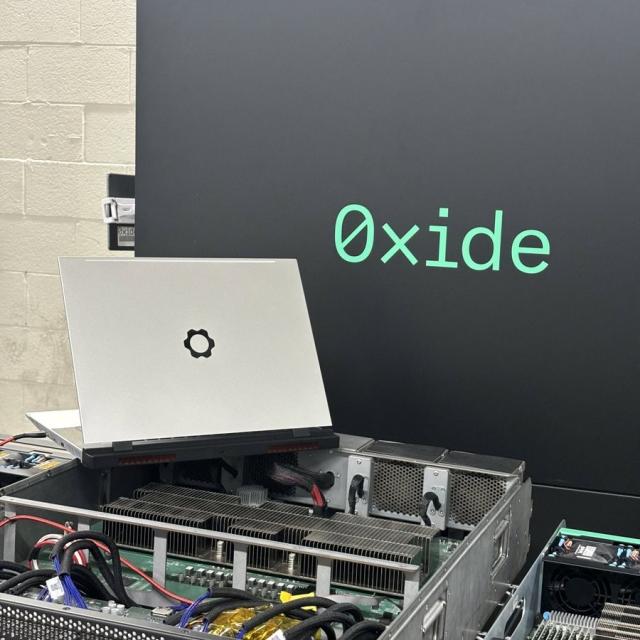 0xide displayed on a screen, Framework Laptop 13 sitting on top of a computer server, placed on its side. 