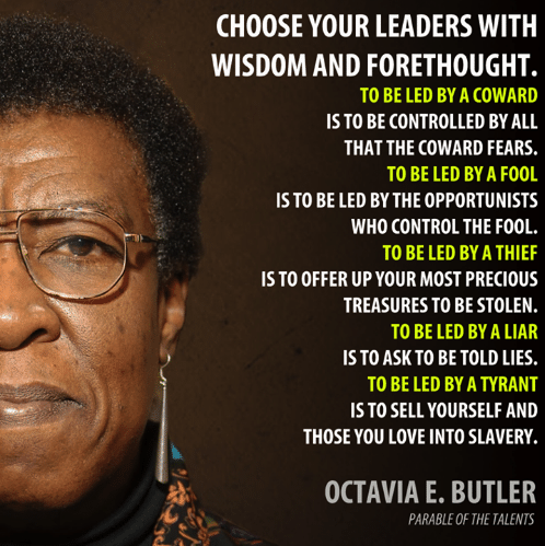 An image of a black woman, wearing glasses, with a determined look on her face (writer, Octavia Butler). Next to her image are the words:

“Choose your leaders
with wisdom and forethought.
To be led by a coward
is to be controlled
by all that the coward fears.
To be led by a fool
is to be led
by the opportunists
who control the fool.
To be led by a thief
is to offer up
your most precious treasures
to be stolen.
To be led by a liar
is to ask
to be told lies.
To be led by a tyrant
is to sell yourself
and those you love
into slavery.”
― Octavia E. Butler
Parable of the Talents 