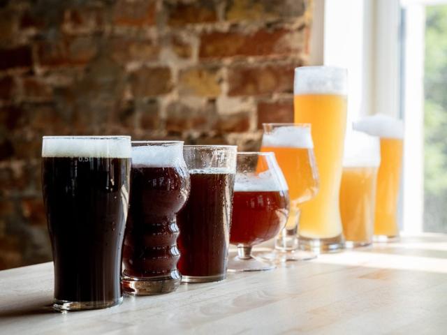 A line of 8 different beers, starting with a dark stout, going through an amber red to a bright unfiltered weizen-like beer. All beers are in different shape glasses.