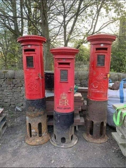 Three red British ER mailboxes with the support structure visible which is about 2/3 of the height of the part of the mailbox you usually see. 