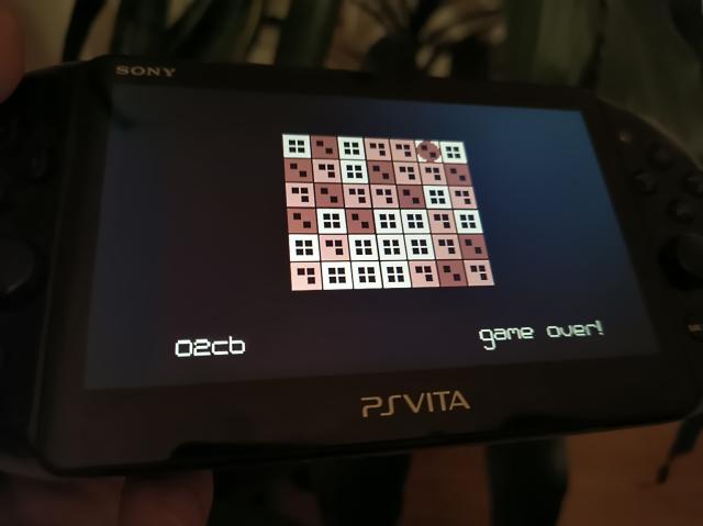 A handheld gaming device with a grid of brown squares with the values 1 to 4 represented by dots. The game is over with a score of 2cb.