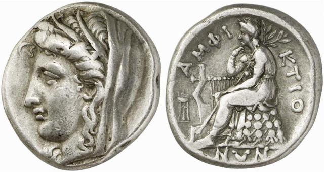 "Head of Demeter to left, wearing wreath of wheat ears and veil ΑΜΦΙ-ΚΤΙΟ-ΝΩΝ, Apollo Pythios, laureate and wearing a chiton, seated left on an omphalos draped with his himation and covered with a network of knotted woolen cords. His right elbow is propped on his kithara, he rests his chin on his right hand and he holds a long laurel branch over his shoulder with his left hand... In the field to left, tripod."

Classical Numismatic Group, Inc. cngcoins.com, CC BY-SA 2.5, via Wikimedia Commons.