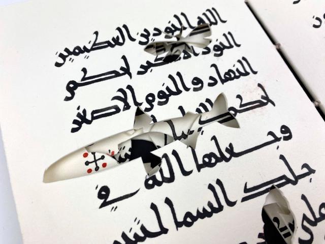 Close up on a page showing the silhouettes of extinct animal species cut throughout the text so that the black inside cover is visible through the holes