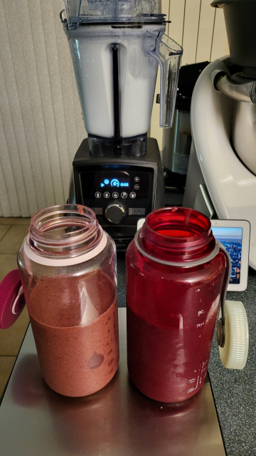 Two wide mouth containers for the smoothie. Behind is a blender is foaming with water & washing up liquid as it self cleans.