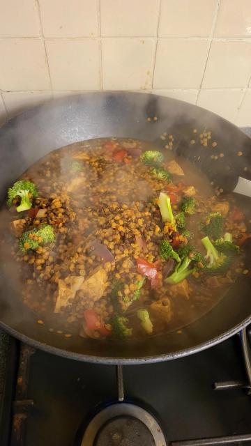 A large wok, on the hob, filled with bubbling ingredients and wreathed in steam. The lentils are happily swelling up absorbing all the liquids & tastes.