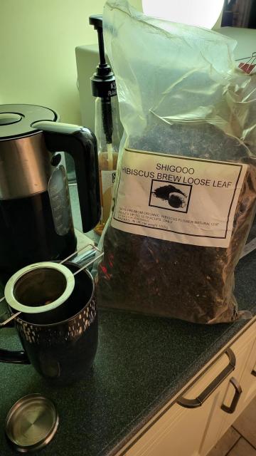 A big bag of dried hibiscus tea on the kitchen counter, next to kettle and mug for brewing.