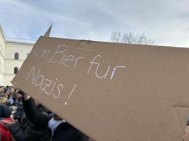 Ein Pappschild mit der Aufschrift "Kein Bier für Nazis!", das bei einer Versammlung hochgehalten wird.