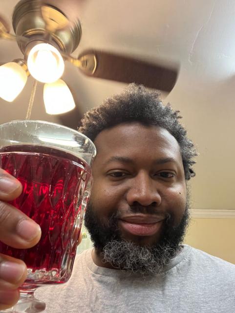 Selfie of me toasting on Fediverse Day. I am holding a glass full of cranberry juice.