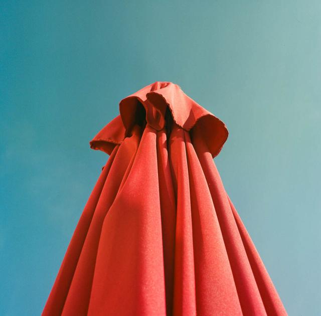 A red parasol against a blue sky.