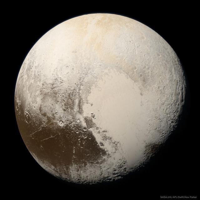 The minor planet Pluto is shown up close, as seen by the passing New Horizons spacecraft, and in true color. Pluto is a complex mix of beige regions and some dark brown regions.