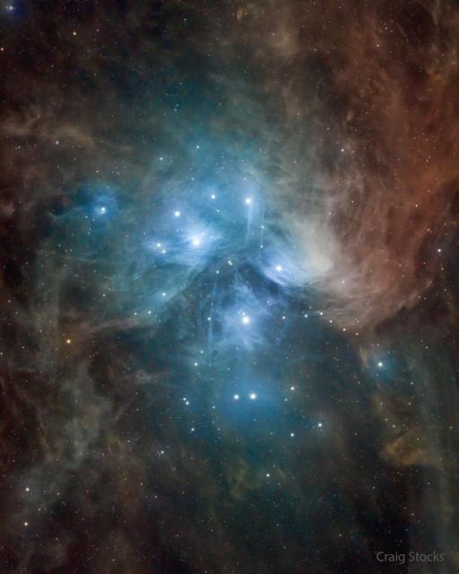 The famous Pleiades star cluster is shown surrounded by dust. Dust near the bright stars reflects blue light, but dust further away appears more red.