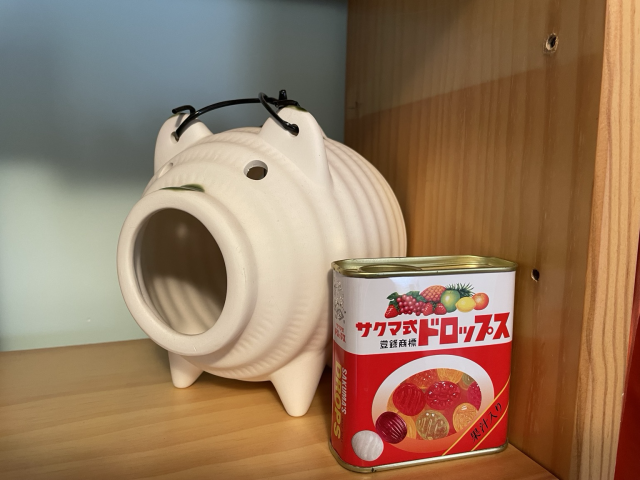 Ceramic pig to burn incense to repel mosquitoes. In front is a Japanese candy can.