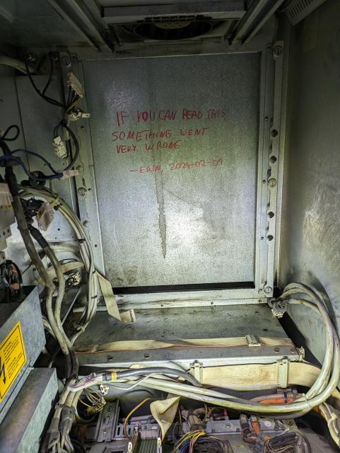 interior photo of a kuka krc1 enclosure with the pm6-600 power module removed and back wall of the enclosure exposed.

there's a message written there in red marker:

"if you can read this, something went very wrong. erin, 2024-02-01"