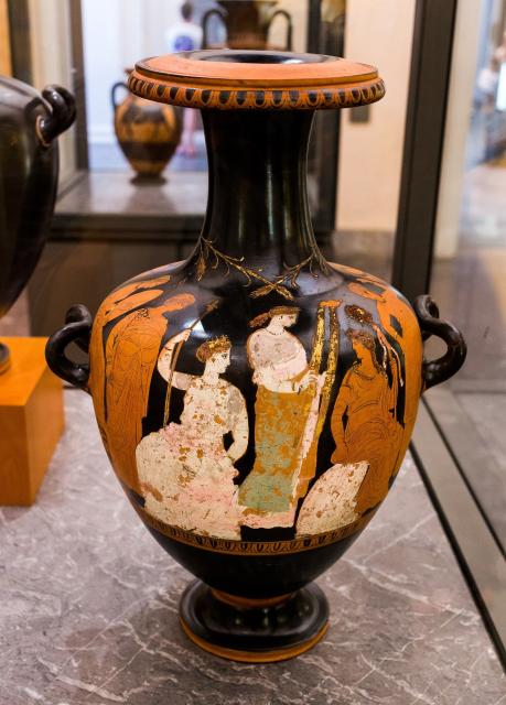 "Demeter seated and Persephone standing with torches, youthful Dionysos with thyrsos seated on the (Delphic?) omphalos, maenads, man in mantle with staff (Triptolemos?)..."

ArchaiOptix, CC BY-SA 4.0, via Wikimedia Commons.