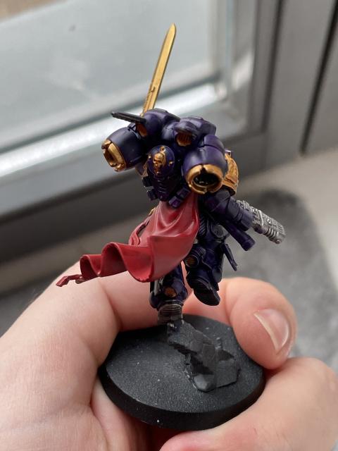 A Space Marine Captain with Jumping Rack painted in purple, red, and gold. Back view.