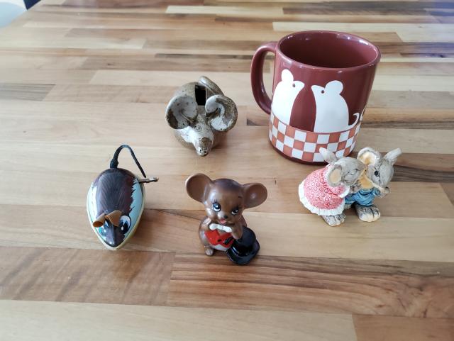 photograph of four toy mice and a coffee mug with two mice silhouettes on it, all on a wooden tabletop