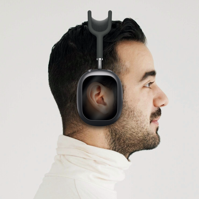 A photoshopped image of a person wearing AirPods Max, but the cups have a display that shows the person’s ear. 