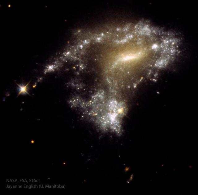 A distorted galaxy is shown with a string of stars trailing off on the left.