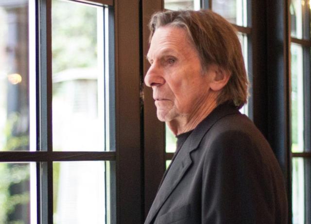 Photo of an octogenarian Leonard Nimoy in a black coat suit jacket and a black shirt looking out of a multi-paned window. Photo by Spencer Davis.
