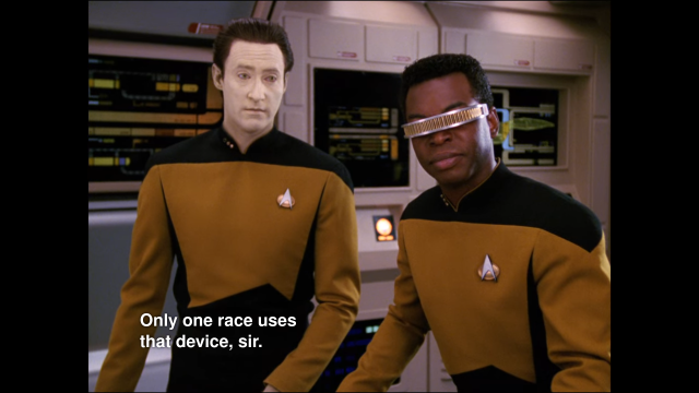 Data and Geordi from Star Trek (pale yellow android, black blind man) stand in the Enterprise's main engineering. Data says: "only one race uses that device, sir."