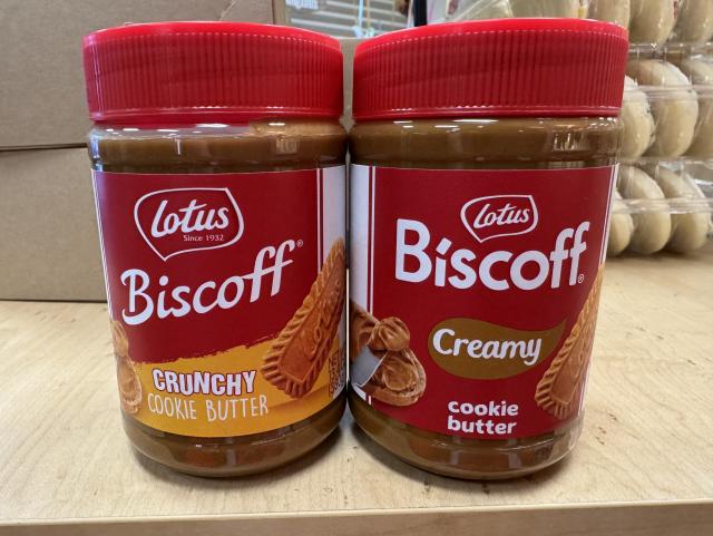 Two jars of Lotus Biscoff spread, one labeled 'Crunchy Cookie Butter' and the other 'Creamy Cookie Butter,' on a wooden surface