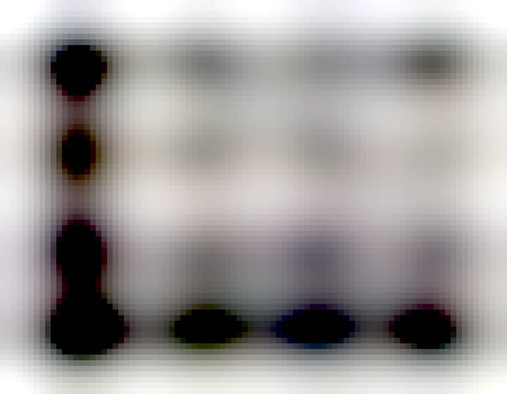 Black and white image of a tree trunk and branches on the left casting a long shadow across a snowy field.