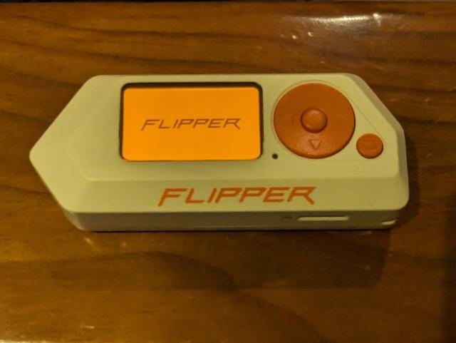 A Flipper Zero with the Flipper logo on screen.
