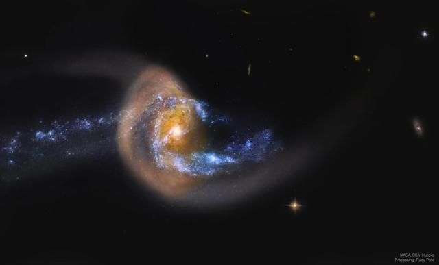 A blue spiral galaxy appears to be colliding -- and possibly moving through -- a dusty brown galaxy.